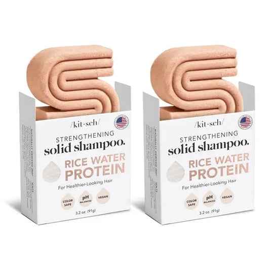 Two boxes of Kitsch All Natural Rice Water Strengthening Shampoo Bar 3.2oz (2 Pack) by Kitsch, featuring pink, S-shaped solid bars partially out of the packaging for healthy hair growth.