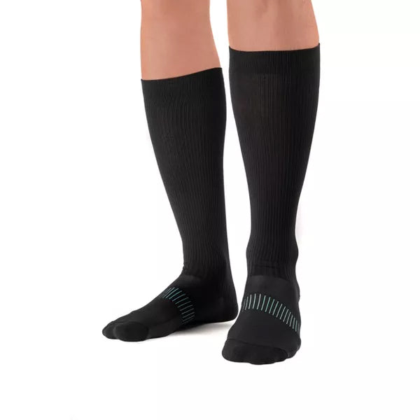 A pair of feet wearing Copper Fit Ice Menthol Infused Compression Socks (S/M, 2 pack) with a ribbed texture and light blue stripes across the top.