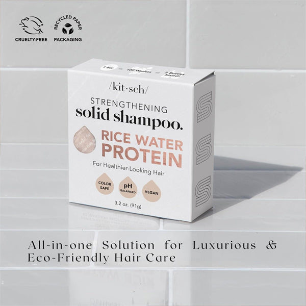 A box of Kitsch 2 Pack All Natural Rice Water Strengthening Shampoo Bars (3.2oz) sits on tiles, with packaging that promotes its cruelty-free, vegan, pH balanced, and eco-friendly benefits for healthy hair.