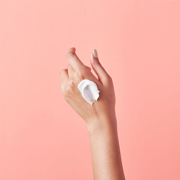 A hand with light skin tone features eos Eucalyptus Natural Shea Butter Hand Lotion (2.5oz, 2 Pack) on the back, emphasizing 24-hour hydration, set against a plain peach background.