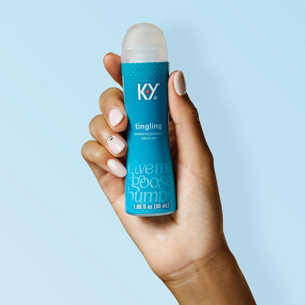 A hand holds a 1.69oz bottle from the 3 Pack - K-Y Tingling Water Based Lube Sensorial Personal Lubricant set against a light blue background.