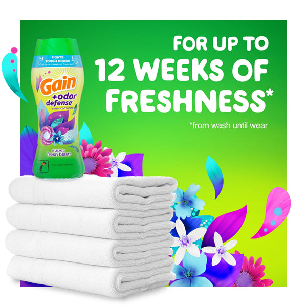 A 5 Pack of Gain + Odor Defense In-Wash Scent Booster Super Fresh Blast Scent 5.7 oz is placed next to folded white towels, with a backdrop stating For up to 12 weeks of lasting freshness* from wash until wear.