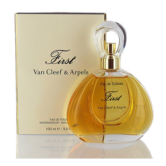 A bottle of First by Van Cleef & Arpels Eau De Toilette for Women 3.3oz is shown in front of its elegant gold box, highlighting this classic fragrance from Van Cleef & Arpels.