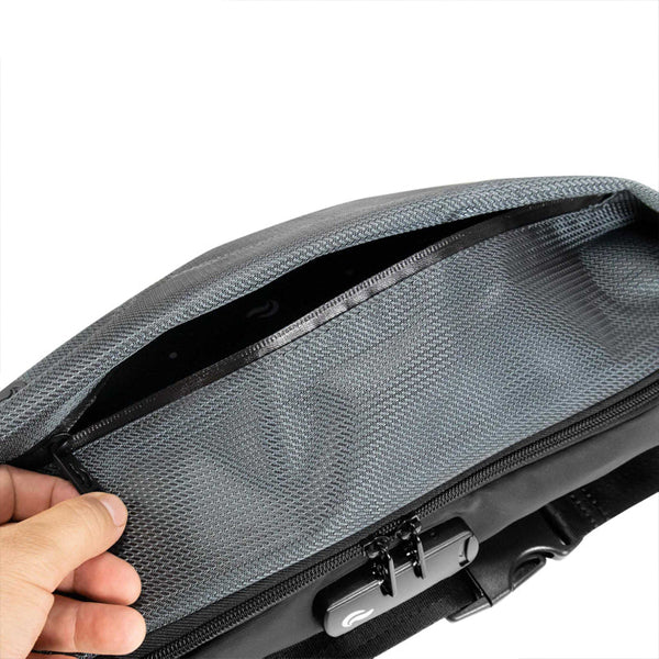 A hand opens the Skunk Drifter Medium Crossbody Bag in Metal Gray, showing its gray mesh inner pocket and zipper, all protected by 100% smell and weather proof carbon lining.