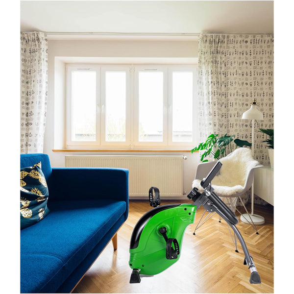 A bright living room with a blue sofa, white chair, ShareVgo Smart Portable Mini Folding Exercise Bike Bluetooth Trainer SPB1000, wooden floor, houseplant, and large window with patterned curtains.