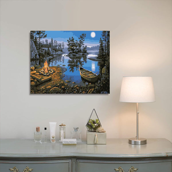 A Ledgebay Paint by Number for Adults Framed Canvas Moonlight Bay (16x20) hangs above a dresser with a lamp, toiletries, and decor.