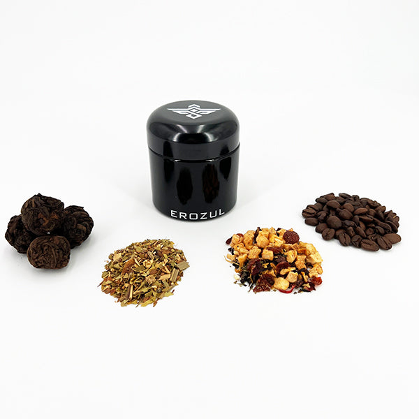 An Erozul 100ml Screw Top Wide Mouth Glass UV Jar by Erozul sits behind four piles of dried ingredients—herbs, dried fruit, coffee beans, and dark round items—against a white background.