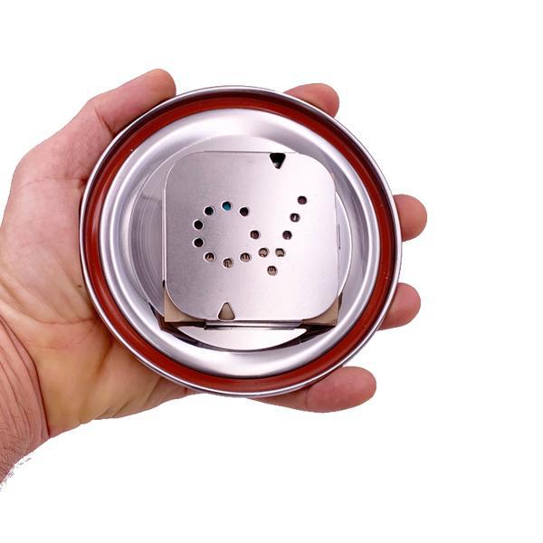 A hand holds the CVault Large Humidity Control Airtight Metal Smell Proof Container lid, featuring a red seal and a square metal plate with S holes—by CVault, perfect for airtight humidity control and odor-proof storage.