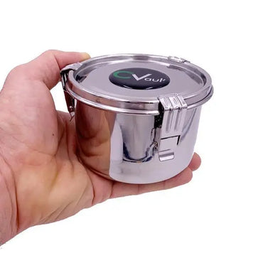 A hand holding a CVault Medium Humidity Control Airtight Metal Stash Smell Proof Container, featuring locking clamps and the CVault logo on the stainless steel lid.