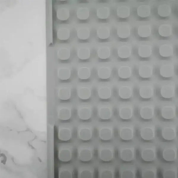 A gray Deal Society Self Draining Silicone Dish Drying Mat (16 x 12, Twin Pack) with raised bumps is placed on a white marble surface.