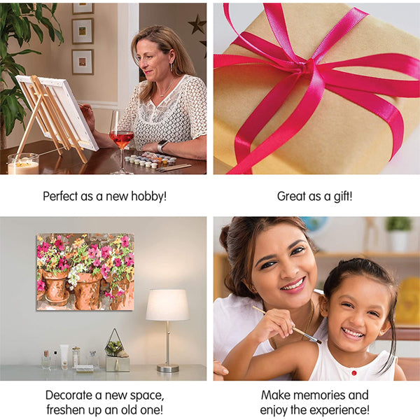 A smiling woman and a young girl enjoy painting together at a table, using the Ledgebay Paint by Numbers Kit for Adults—Sweet Petunias (16 x 20 framed) by Ledgebay, with a floral painting and gift wrapped in pink ribbon nearby.