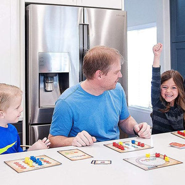 Three people play Inspiration Play Rail Wreck Kids Train-Themed Toddler Preschool Educational Board Game; a girl on the right raises her arm and smiles as the others look at her.