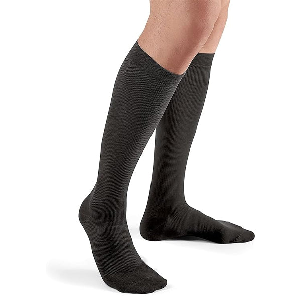 A person wears Futura 2 Pack FUTURO Lifestyle Black Compression Dress Socks for Men, Firm, Large, standing on a white background.